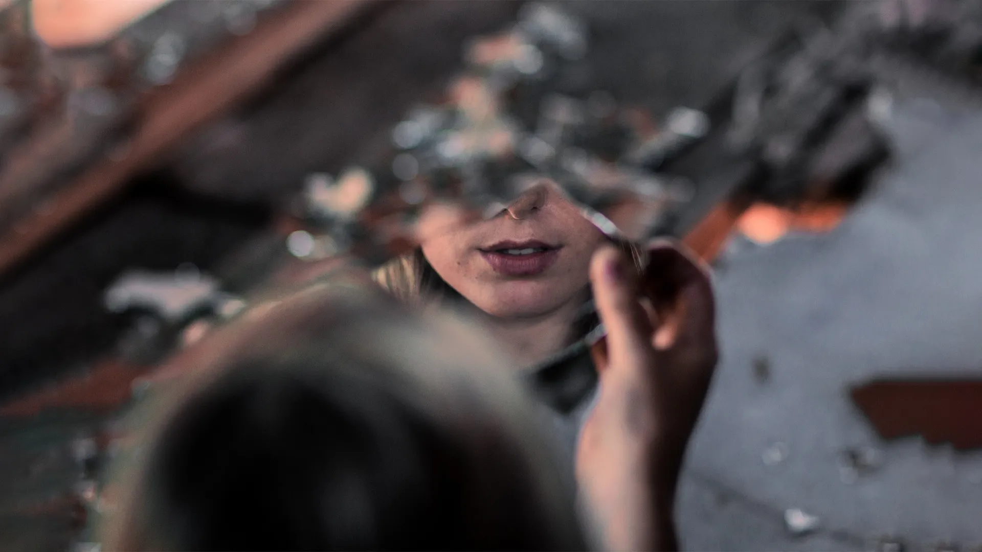 Reflet partiel du visage d’une femme dans un miroir brisé